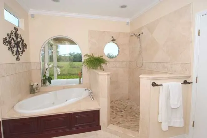 Beige tiled bathroom with a drop-in soaking tub and a walk-in shower
