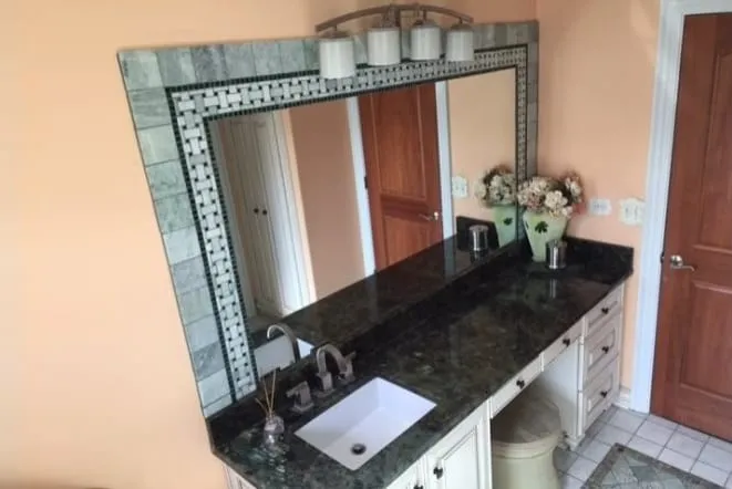 Black granite vanity with an integrated makeup station and a decorative mirror