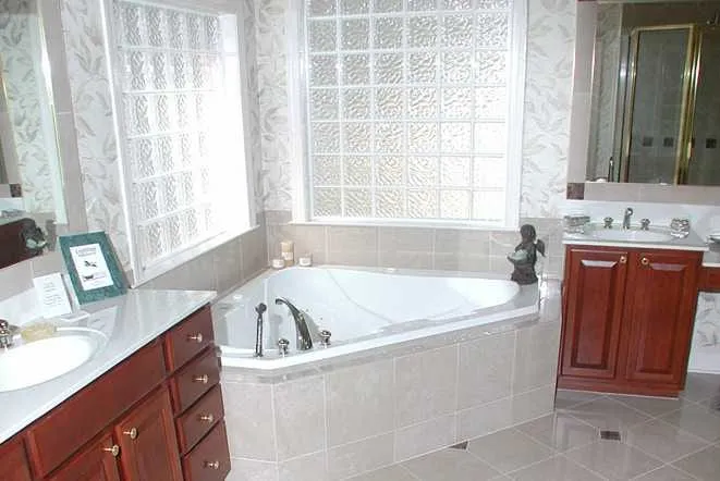 Corner tub with a stone deck beneath a glass block window