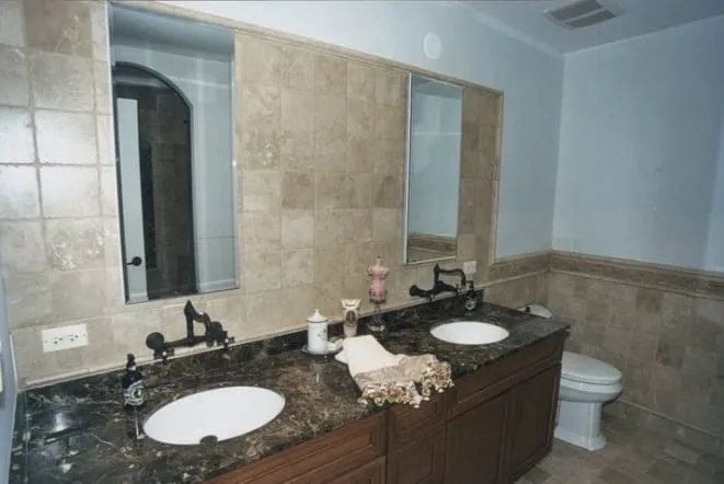 Dark granite double vanity in a beige tiled bathroom