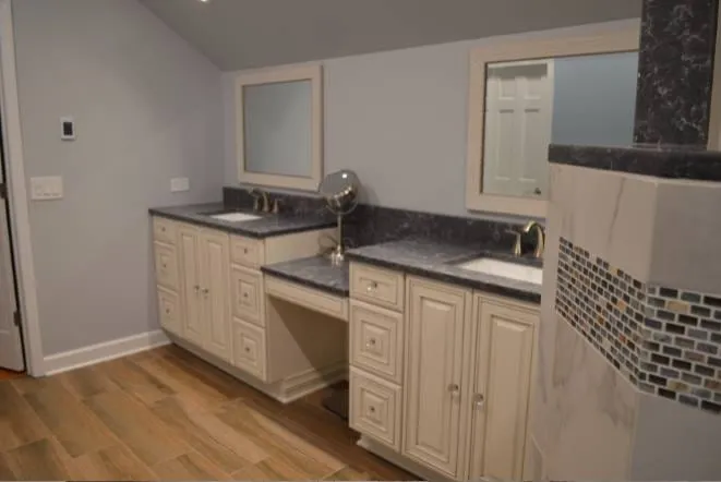 Cream cabinets with a dark granite vanity top and a mosaic tile accent stripe