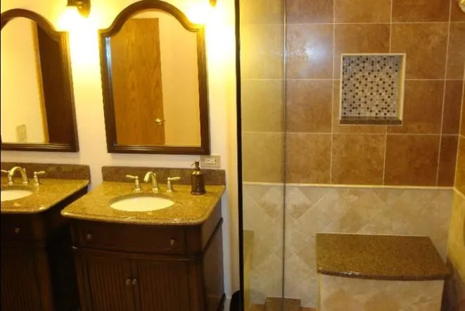 Double vanity with gold granite top and two arched mirrors