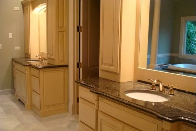 Gold granite double vanity top on maple cabinetry with a framed mirror