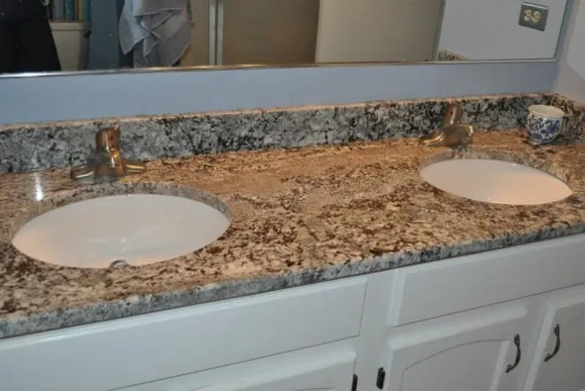 Gold granite double vanity top on white cabinets with brushed fixtures