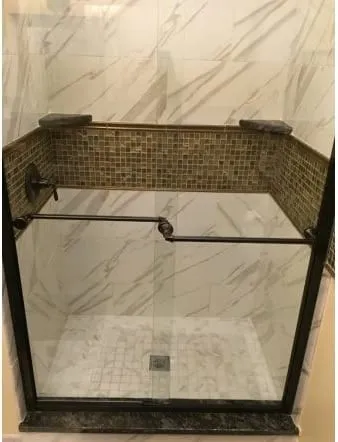 Marble-lined shower with a fixed glass panel and mosaic border
