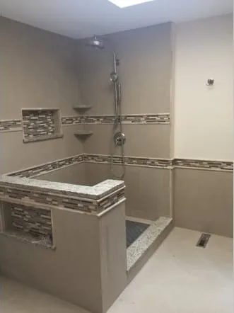 Curbed shower with a granite threshold and mosaic accent tile