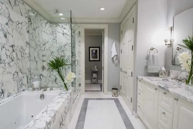 White marble bathroom with a drop-in tub and a glass-enclosed shower
