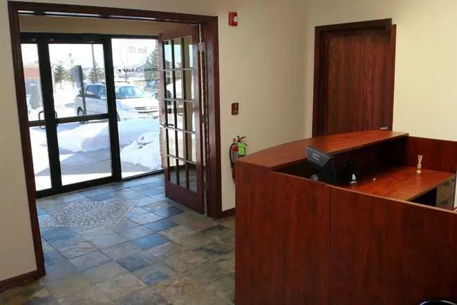 Office reception desk with a stone counter beside the entry doors