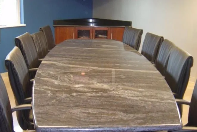Long conference table topped in travertine-toned stone