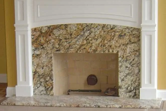 Gold granite fireplace surround beneath a white mantel