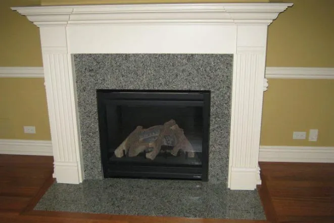 Grey granite fireplace surround and hearth with a white mantel