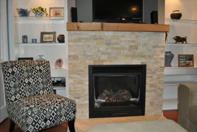 Stacked stone fireplace with a rustic wood mantel and flanking shelves