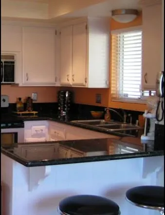 Black granite peninsula with bar stools and white cabinetry