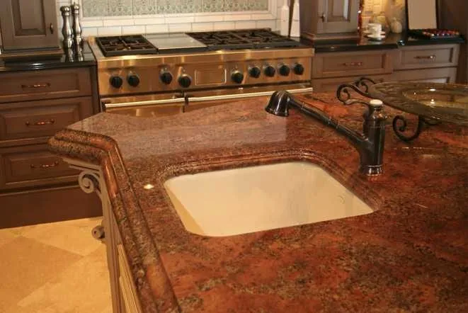 Warm brown granite countertop with a drop-in cooktop and undermount sink