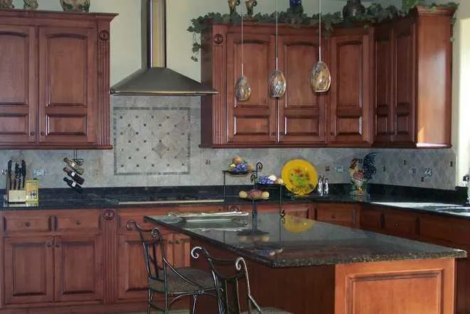 Dark granite island with bar stools in a cherry-cabinet kitchen