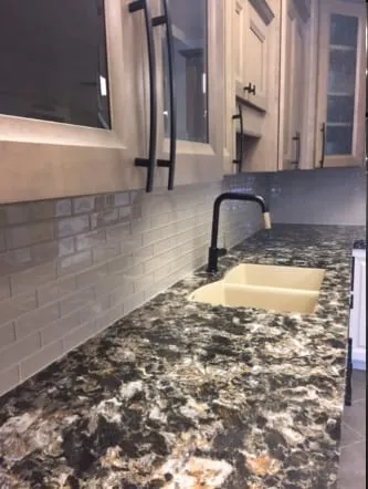 Dark granite counter with an undermount sink and white subway tile backsplash