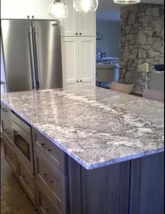 Grey and white granite island beside a stacked stone wall