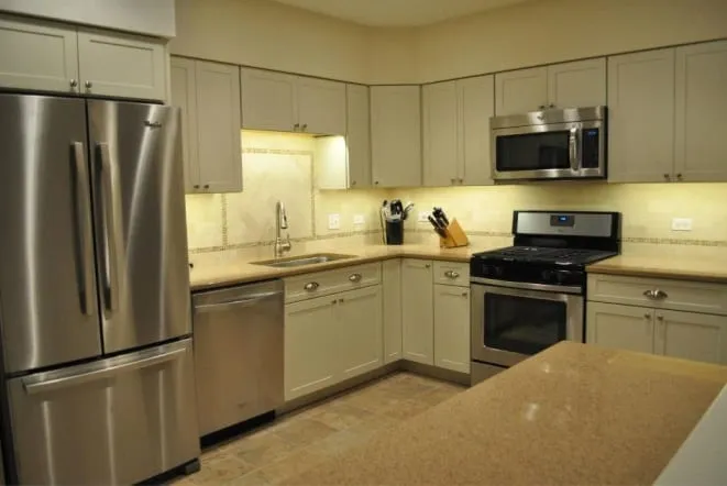 Contemporary white kitchen with light stone countertops and stainless appliances