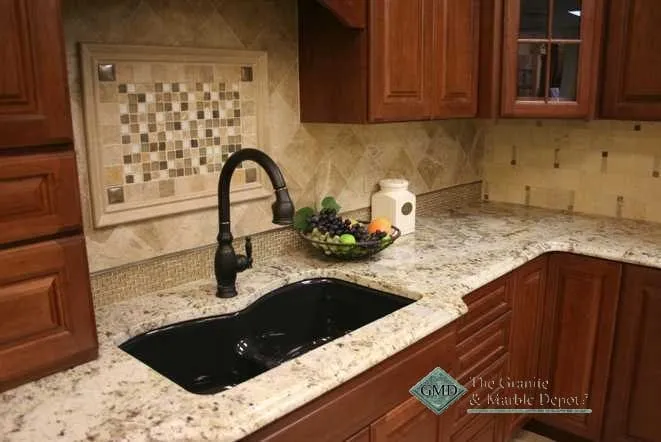 Light granite countertop with a black undermount sink and mosaic tile backsplash