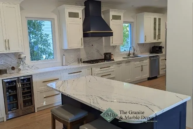 Marble-look quartz island over a navy base, with a matching slab backsplash behind the range and a built-in wine refrigerator