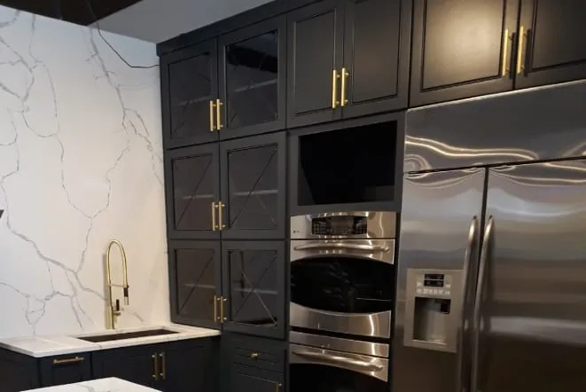 Navy cabinets with gold hardware and a veined white quartz counter and backsplash