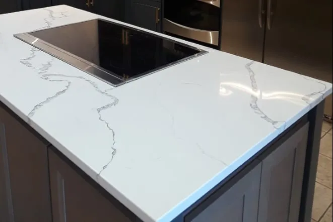 Close view of a veined white quartz countertop around a flush induction cooktop