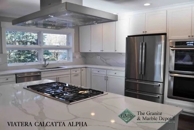White Viatera Calacatta quartz counters with a gas cooktop and stainless wall ovens