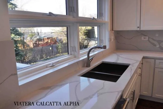 White Viatera Calacatta quartz countertop with a black undermount sink beneath a picture window