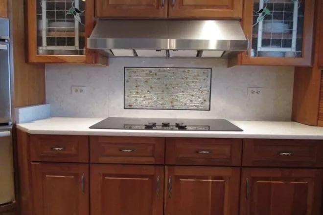 Cherry cabinets with white stone countertops and a downdraft cooktop