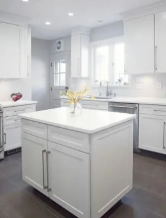 All-white kitchen with a white stone island and shaker cabinets