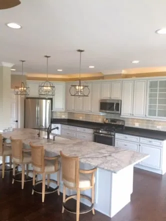 White marble-topped island with bar stools in a bright white kitchen