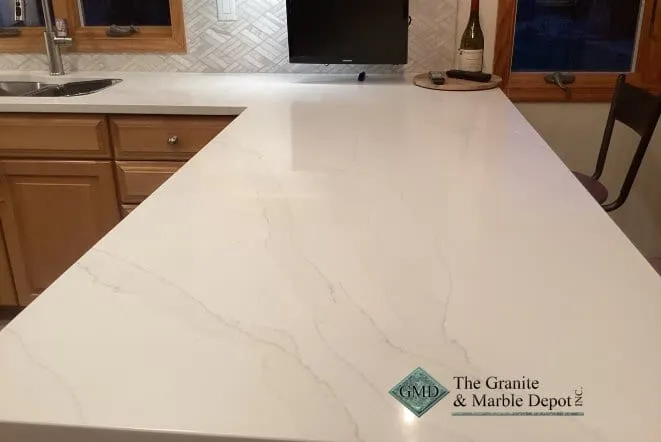 White quartz countertop with soft grey veining running past a herringbone tile backsplash