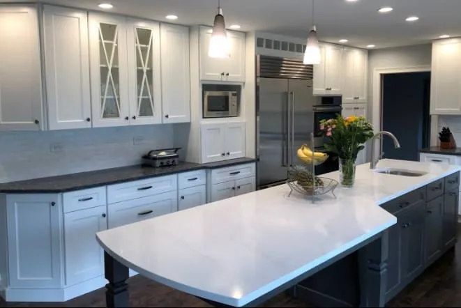 White quartz island with a rounded end above blue-grey cabinetry