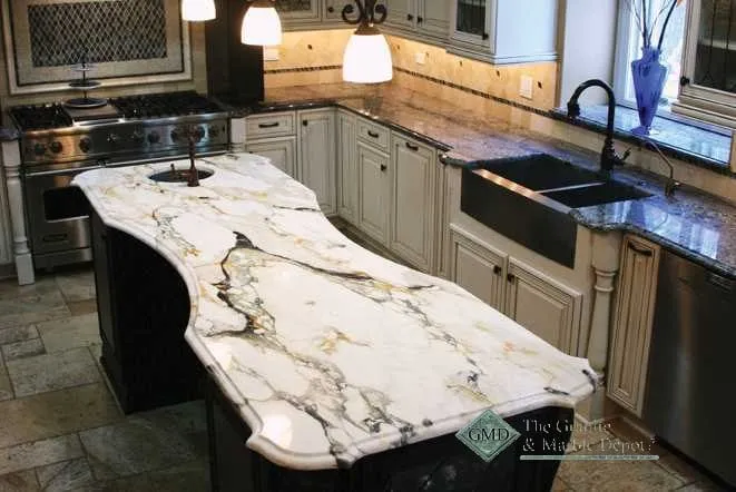 Kitchen island topped with dramatically veined white and gold granite over dark cabinetry