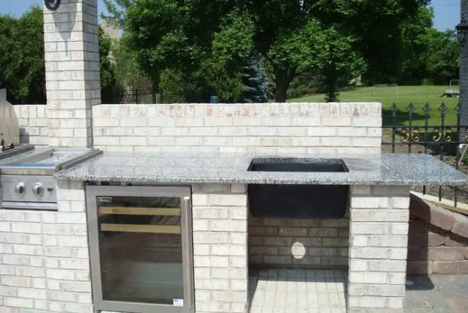 Outdoor kitchen with black stone counters over a cut stone base