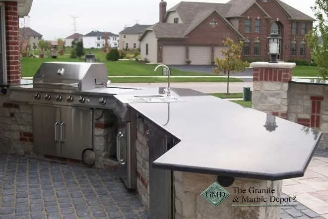 Outdoor kitchen island with a built-in grill and grey stone countertops