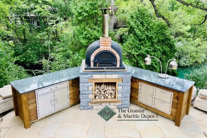 Outdoor pizza oven flanked by stone counters and cabinets