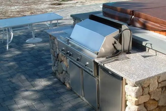 Poolside outdoor kitchen with a stainless grill and stone counters